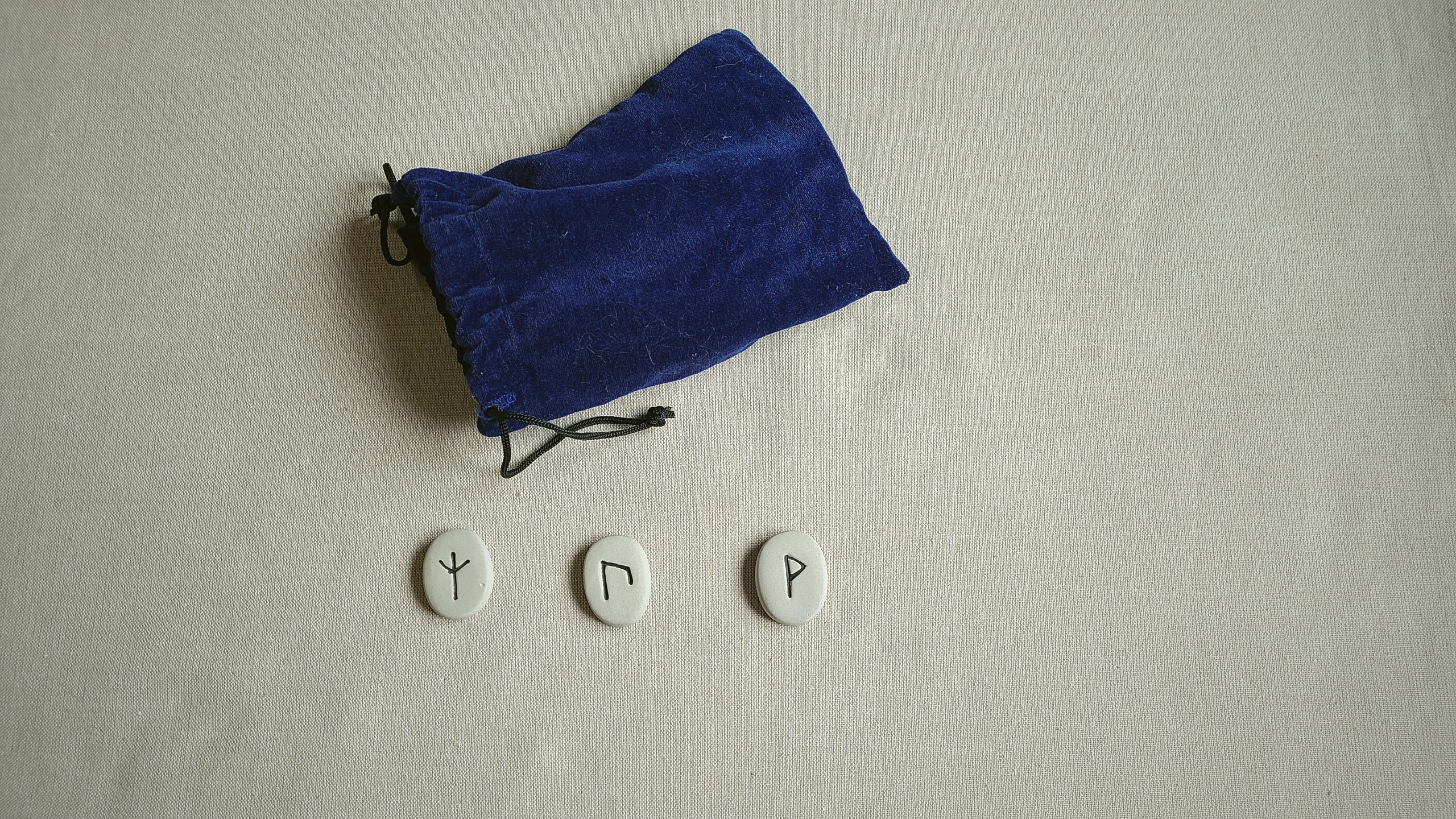 A three-rune reading laid in a row beside the pouch