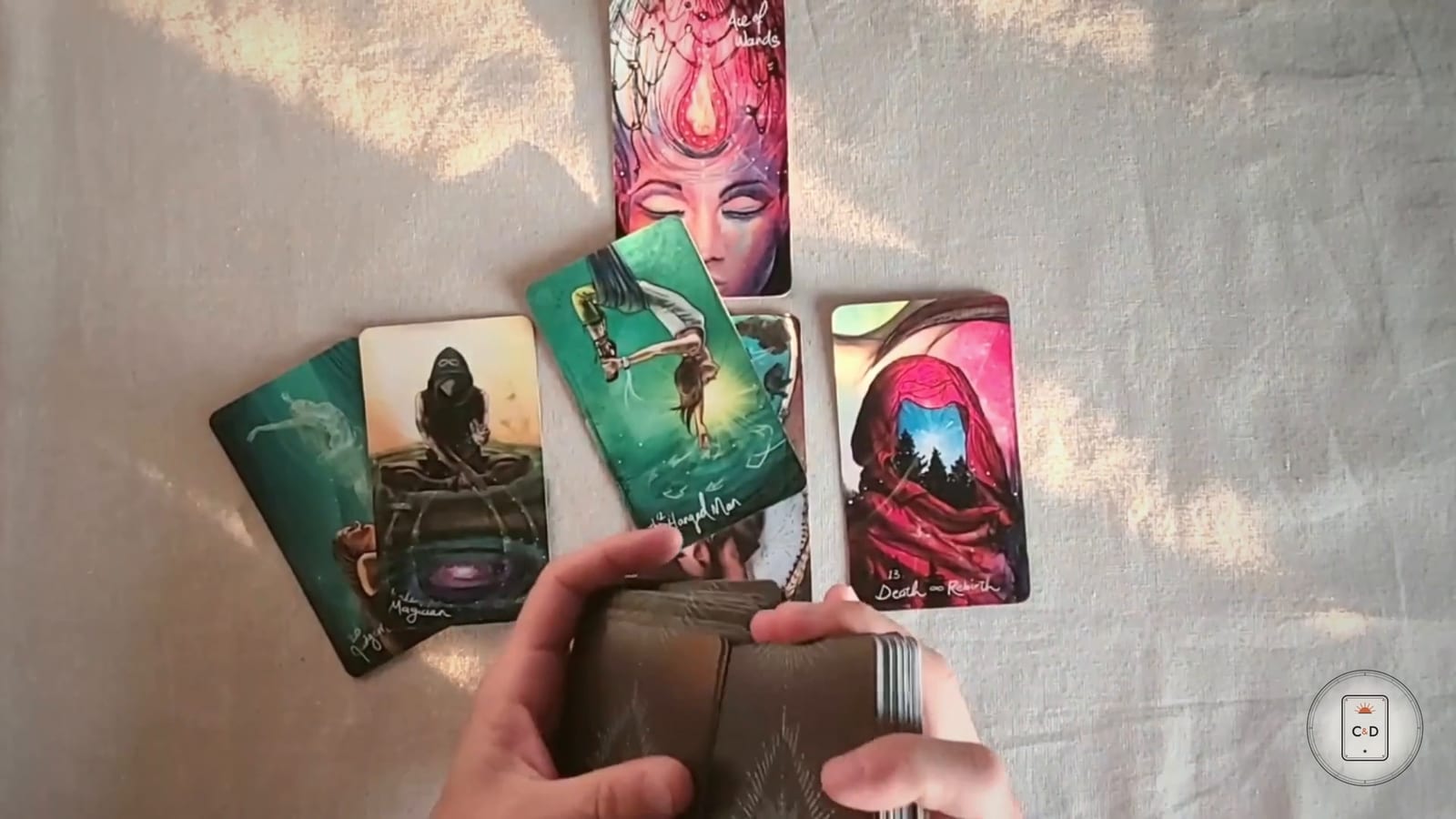 How does tarot work: a reader dealing a Celtic Cross by hand, four cards laid on linen and the deck still held